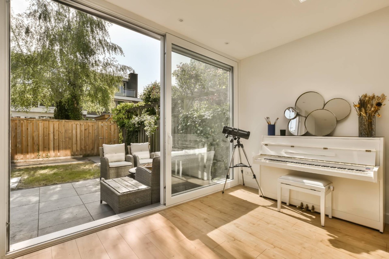 A sliding patio door without shades or blinds in a living room with a piano at Smart PNW near Tacoma, WA